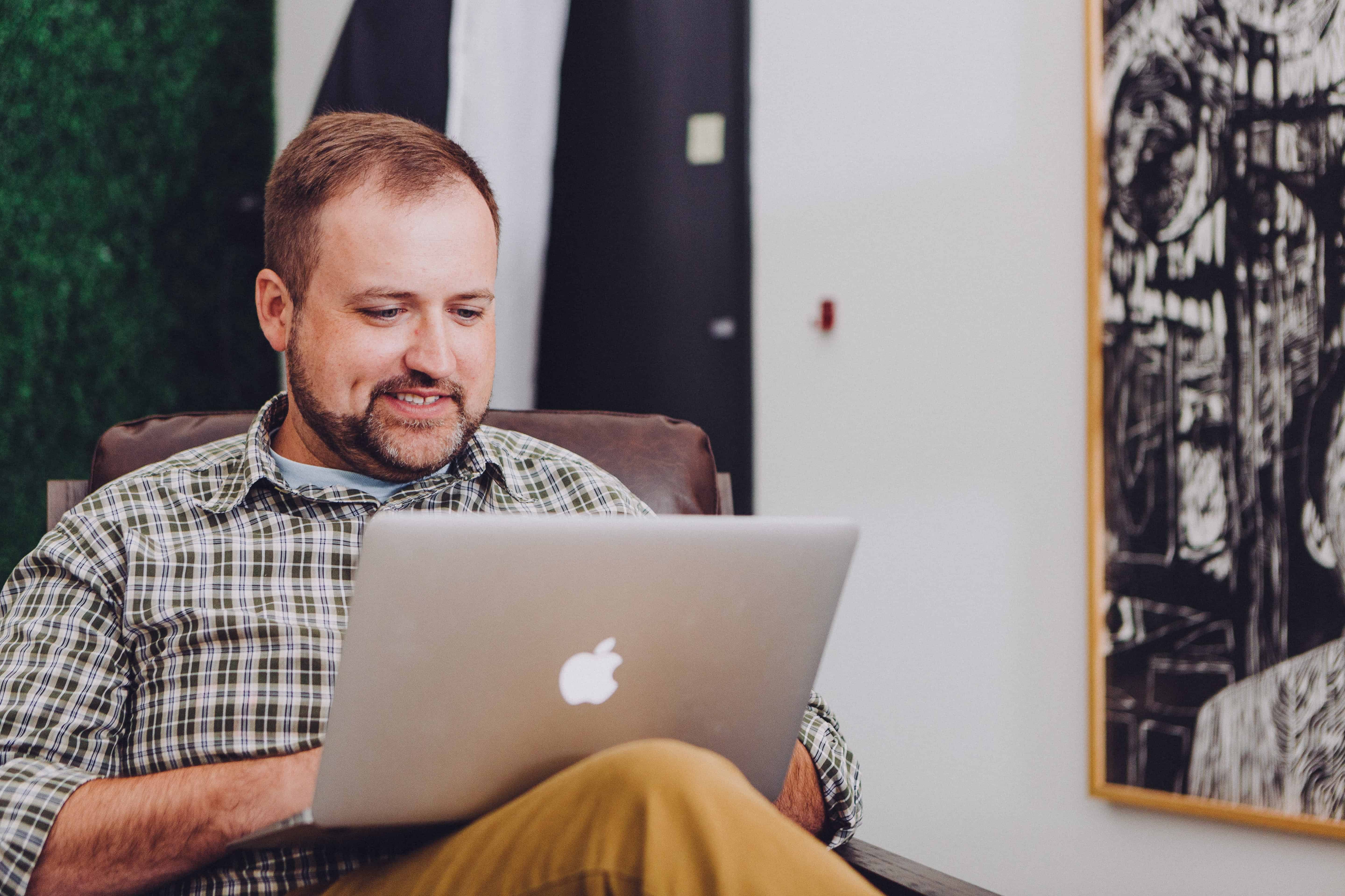 Happy man reading a book on a laptop