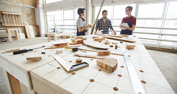 view of a wood work table with people standing in background