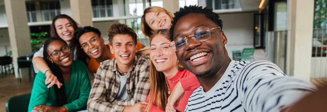Smiling students taking group selfie